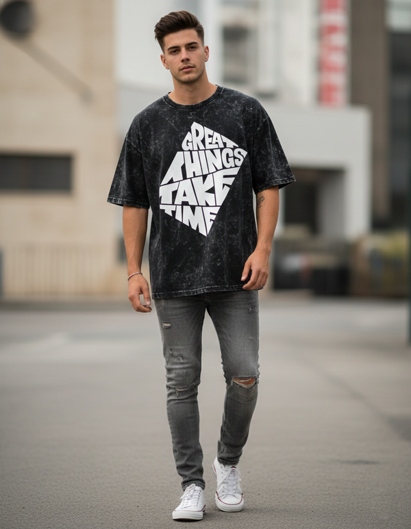 Man wearing a black t-shirt with white text and ripped jeans standing on a street.