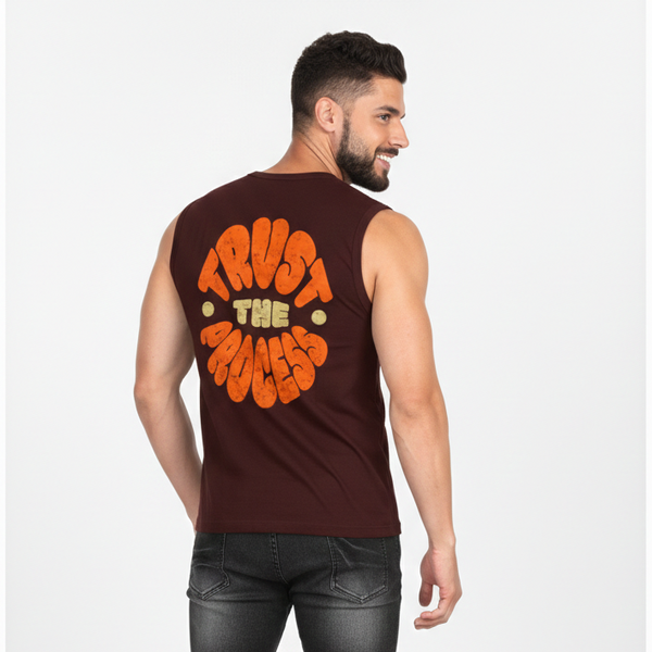 Man wearing a sleeveless brown shirt with 'Trust The Process' text on the back, standing against a white background.